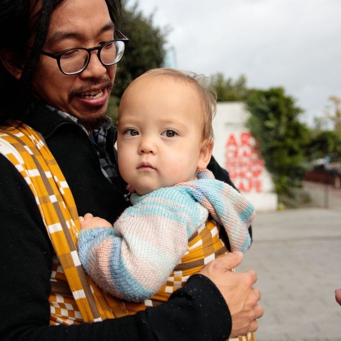 Dad with wrap, dreadlocks small baby benefits of babywearing