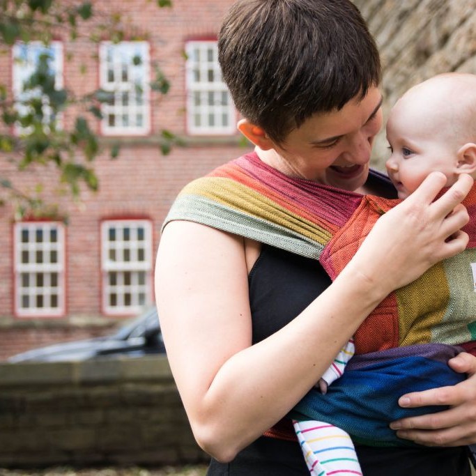 Benefits of babywearing mum with colourful rainbow meh dai playing small baby